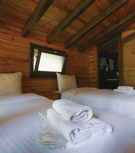 cuarto con camas estilo cabaña con paredes de madera y ropa de cama blanca